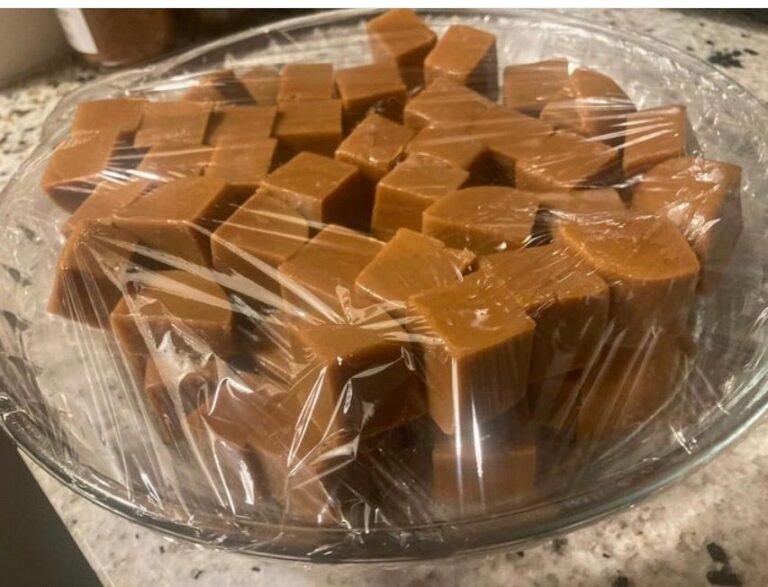 a plate of homemade caramel squares covered in plastic wrap