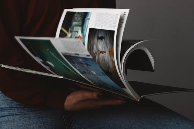 person with black nail polish flipping through a magazine