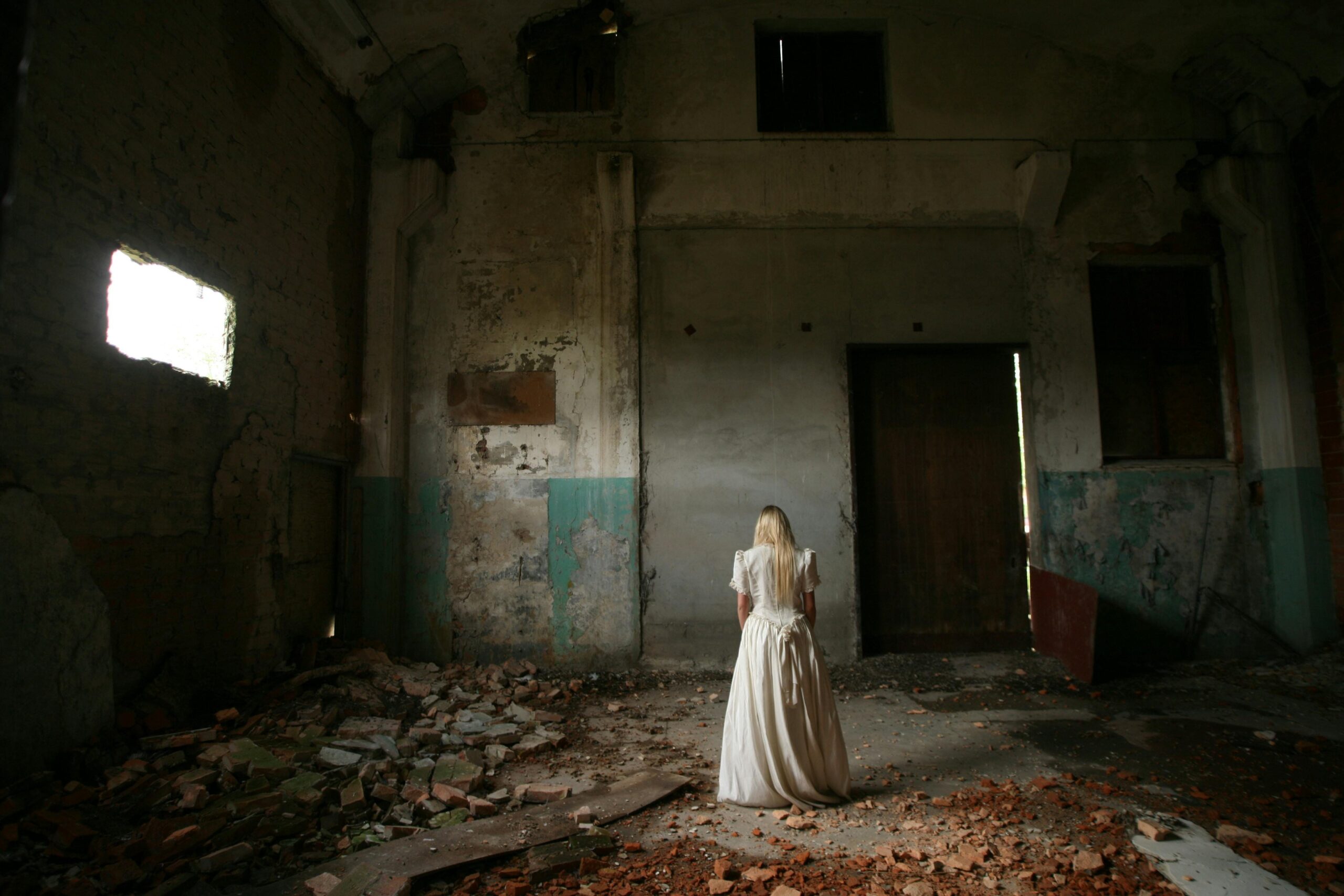 a woman stands with her back to the camera in a ruinous building