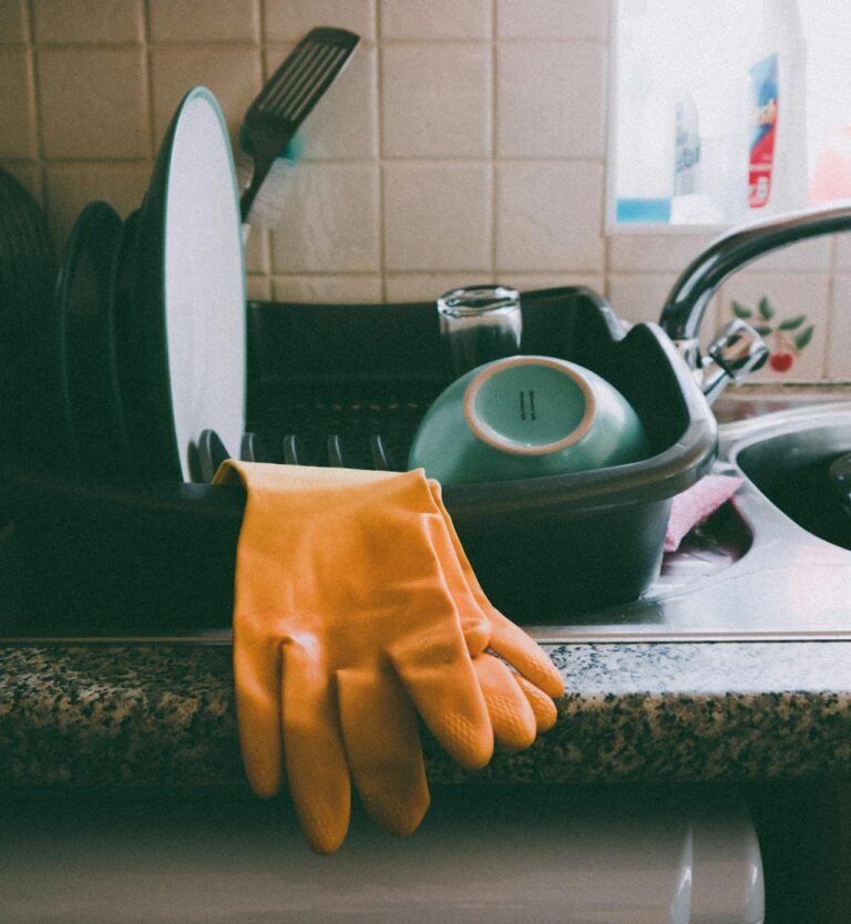 Cozy kitchen setup featuring a dish rack, dishes, and yellow gloves, ideal for a homey atmosphere.