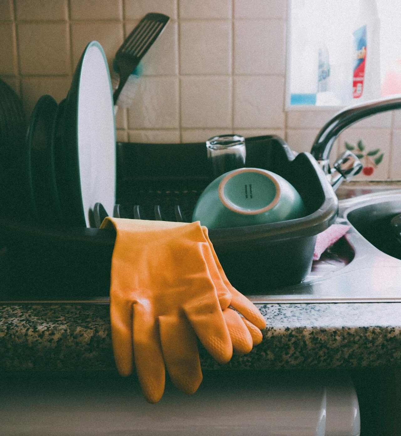 Cozy kitchen setup featuring a dish rack, dishes, and yellow gloves, ideal for a homey atmosphere.